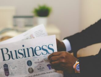 Image montrant un homme tenant un journal avec écrit Business sur la première page pouvant représenter la notion de financement des ventes.